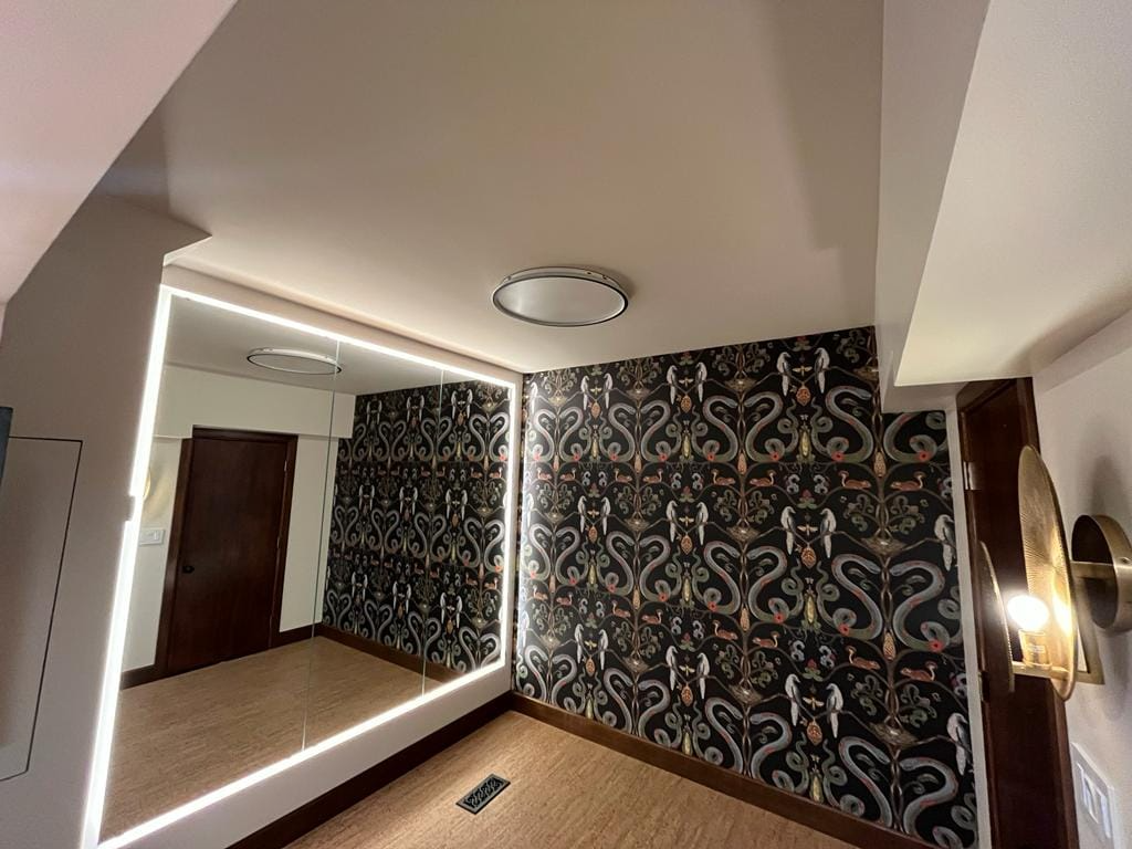 Powder room with a bold black patterned wallpaper featuring cranes and florals, alongside an illuminated LED-frame mirror