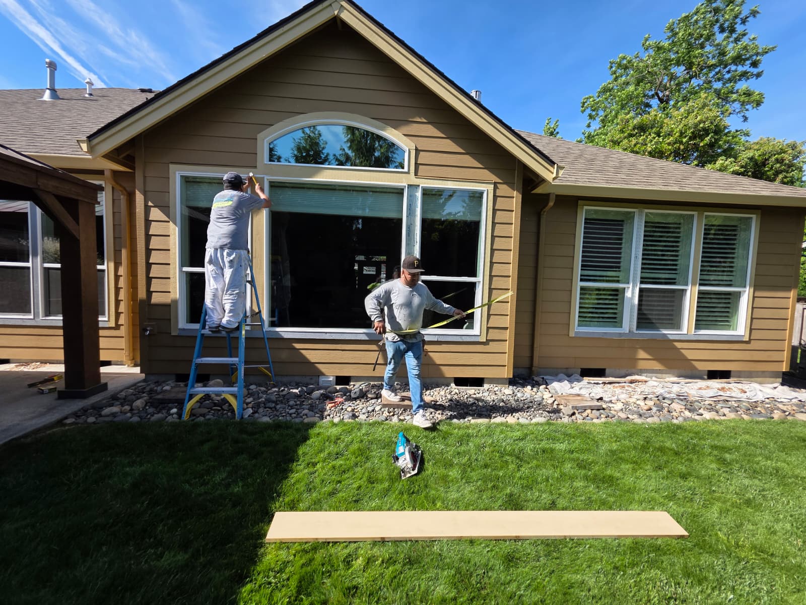 Crew members preparing and painting exterior window trim on a residential home